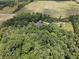An aerial view showcases a house and outbuildings nestled within a dense forest at 5607 E 500 N, Greenfield, IN 46140