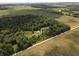 Aerial view of property featuring a house, outbuildings, surrounded by trees and farmland in a rural setting at 5607 E 500 N, Greenfield, IN 46140