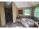 Bathroom with stone accented tub, walk-in shower, window with blinds, and tile flooring at 5607 E 500 N, Greenfield, IN 46140