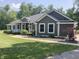 Inviting home with a covered porch and manicured lawn, surrounded by lush greenery, under a clear sky at 5607 E 500 N, Greenfield, IN 46140