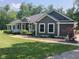 Charming single-story home with a covered porch, dark siding, and manicured landscaping on a sunny day at 5607 E 500 N, Greenfield, IN 46140