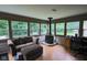 Bright sunroom with wood stove, ample windows showcasing the wooded backyard, and comfortable seating area at 5607 E 500 N, Greenfield, IN 46140