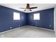 This blue bedroom features gray carpeting, a ceiling fan and two bright windows at 5846 Linton Ln, Indianapolis, IN 46220