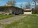 Charming single-story home with stone exterior and detached garage, surrounded by lush green grass and landscaping at 6736 E Michigan St, Indianapolis, IN 46219