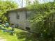 A stone-sided house with some landscaping features and the back of a trailer visible in the yard at 6736 E Michigan St, Indianapolis, IN 46219