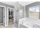 Bright bathroom featuring a glass block shower, soaking tub, and walk-in closet nearby at 6758 Woodcliff Cir, Zionsville, IN 46077