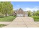 Charming brick home featuring a well-manicured lawn, mature trees, and an attached two-car garage at 6758 Woodcliff Cir, Zionsville, IN 46077