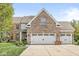 Detailed front view of a brick house showing the driveway, garage doors, and the front facade at 6758 Woodcliff Cir, Zionsville, IN 46077