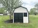 Charming outdoor storage shed with a black door and trim, nestled in a lush green yard at 6811 S Meridian St, Indianapolis, IN 46217