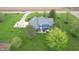 Aerial view of the back of a blue home featuring a stone patio, hot tub, lush landscaping, and large yard at 7020 N 375 E, Lebanon, IN 46052