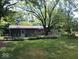 Well-maintained backyard featuring a deck, lush greenery and mature trees providing shade and privacy at 8728 Holliday Dr, Indianapolis, IN 46260