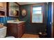 Bathroom featuring dark blue walls, wooden vanity, vintage mirror, and wood-trimmed window at 901 Center Dr, Noblesville, IN 46060