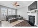 Cozy living room featuring a fireplace, comfortable gray sectional, bright windows, and a stylish ceiling fan at 9422 Oakley Dr, Indianapolis, IN 46260
