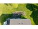 Aerial shot of a backyard deck with table and chairs, surrounded by green grass and mature trees at 950 Hearthside Dr, Brownsburg, IN 46112