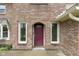 Close-up of a red front door framed by white trim and brick, creating a welcoming entrance at 960 Arrowwood Dr, Carmel, IN 46033