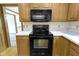 Kitchen featuring black appliances, wood cabinets, and an adjacent room with warm paint at 960 Arrowwood Dr, Carmel, IN 46033