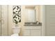 A well-lit bathroom featuring a toilet and vanity with grey countertop, and modern decorative artwork on the wall at 11528 Aubrey Ln, Fishers, IN 46040