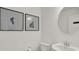 Stylish bathroom with a round mirror, white sink, toilet and framed botanical art pieces at 11612 Aubrey Ln, Fishers, IN 46040