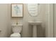 Cozy powder room with pedestal sink, oval mirror, and framed botanical art at 11641 Aubrey Ln, Fishers, IN 46040