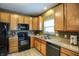 Efficient kitchen with wood cabinetry, black appliances, and a view to the adjacent dining area at 11716 Whisper Cove Dr, Fishers, IN 46037