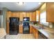 Well-lit kitchen featuring wood cabinets, black appliances, and laminate countertops at 11716 Whisper Cove Dr, Fishers, IN 46037