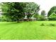 Ranch-style home with a brick facade, surrounded by mature trees and a lush green lawn at 12087 N Gasburg Rd, Mooresville, IN 46158