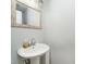 A powder room with a pedestal sink, decorative mirror, and neutral wall paint at 162 Carmelaire Dr, Carmel, IN 46032