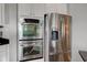 Stainless steel double oven and refrigerator featured in kitchen with white cabinets and black countertops at 1662 Cascade Dr, Greenwood, IN 46143