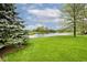 Backyard view with a large pond in the distance, mature trees, and green grass at 19185 Rioux Grove Ct, Noblesville, IN 46062