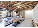 Large open basement featuring exposed beams, a grey sectional sofa, and gym area at 19185 Rioux Grove Ct, Noblesville, IN 46062