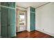Bedroom with wood floors, vintage wallpaper, window, and built-in teal closets at 301 Colescott St, Shelbyville, IN 46176