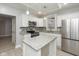 Bright kitchen boasts white cabinets, granite countertops, stainless steel appliances, and an island at 3180 Graceland Ave, Indianapolis, IN 46208