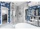 This bathroom showcases a bathtub, walk-in shower, bright blue and white wallpaper, and modern fixtures and hardware at 4134 N Pennsylvania St, Indianapolis, IN 46205
