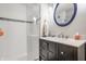 Bathroom with a modern vanity, a round mirror, and a glass-enclosed tiled shower at 4134 N Pennsylvania St, Indianapolis, IN 46205