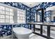 A stylish bathroom showcases an elegant clawfoot tub with bright blue and white wallpaper and natural light from the large windows at 4134 N Pennsylvania St, Indianapolis, IN 46205