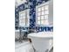 A stylish bathroom showcases an elegant clawfoot tub with bright blue and white wallpaper and natural light from the large windows at 4134 N Pennsylvania St, Indianapolis, IN 46205