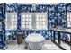 A stylish bathroom showcases an elegant clawfoot tub with bright blue and white wallpaper and natural light from the large windows at 4134 N Pennsylvania St, Indianapolis, IN 46205