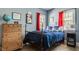 Comfortable bedroom featuring a wooden bed, dresser, natural light from a large window, and bright colored decor and artwork at 4134 N Pennsylvania St, Indianapolis, IN 46205