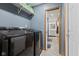 Laundry room with black front load washer and dryer with a shelf overhead and doorway to bathroom at 5168 E Walnut Dr, Mooresville, IN 46158