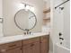 Modern bathroom featuring a wood vanity, round mirror, and white subway tile shower and tub at 579 Exmoor Dr, Carmel, IN 46032