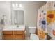 Well-lit bathroom with a wood vanity, modern sink, and decorative floral shower curtain at 5876 E 126Th St, Carmel, IN 46033