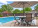 Outdoor dining area with patio furniture and a sun umbrella next to a sparkling pool at 601 Ridgeview Ln, Columbus, IN 47201