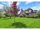 Backyard featuring a brick house, a spacious lawn, mature trees, and landscaping at 621 Thorne Dr, Brownsburg, IN 46112