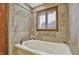 Comfortable bathtub with travertine tile surround and a window for natural light at 621 Thorne Dr, Brownsburg, IN 46112