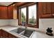 A large double-basin sink with a picture window above surrounded by oak cabinets and a white subway tile backsplash at 621 Thorne Dr, Brownsburg, IN 46112