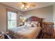 Comfortable bedroom with a decorative comforter, ornate headboard, ceiling fan, and natural light from the window at 6212 Rocklane Rd, Greenwood, IN 46143