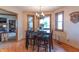 A dining room with a view through wood-framed windows, complemented by a modern chandelier and wood floors at 6212 Rocklane Rd, Greenwood, IN 46143