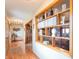 Hallway with hardwood floors and built-in shelving displaying decorative items and a doorway to a room with a large leather sofa at 6212 Rocklane Rd, Greenwood, IN 46143