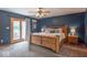 Main bedroom with blue walls, a wooden bed frame, and natural light streaming through a glass door to the outside at 6212 Rocklane Rd, Greenwood, IN 46143