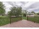 A view of the backyard with mature tree and partial lake view, as seen from the wooden deck at 6337 Whitaker Farms Dr, Indianapolis, IN 46237